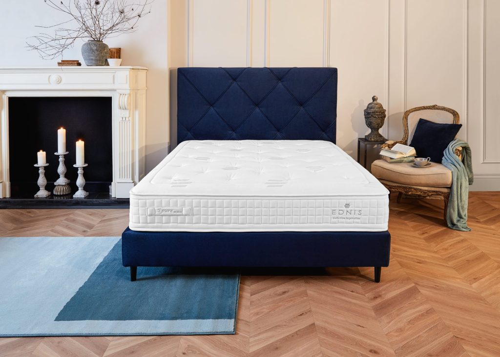 Colchão Ednis Epure numa cama azul, num quarto com lareira