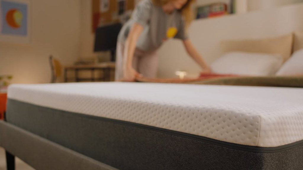 Mulher a fazer a cama com um colchão Emma Original Classic+