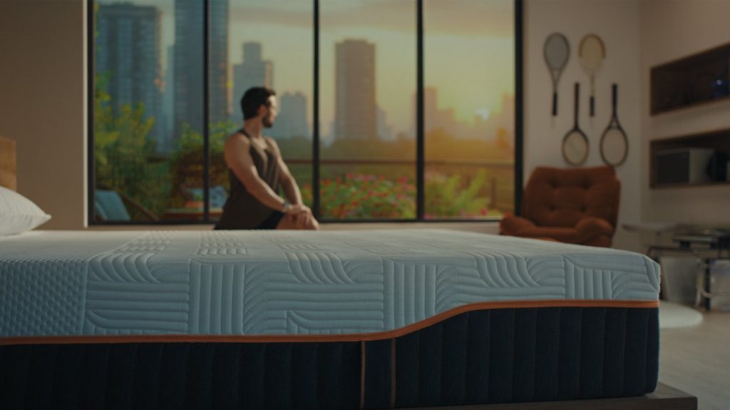 Homem sentado num colchão Emma Performance num quarto