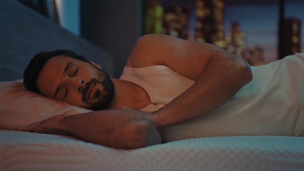 Homem a dormir de lado num colchão Emma Performance