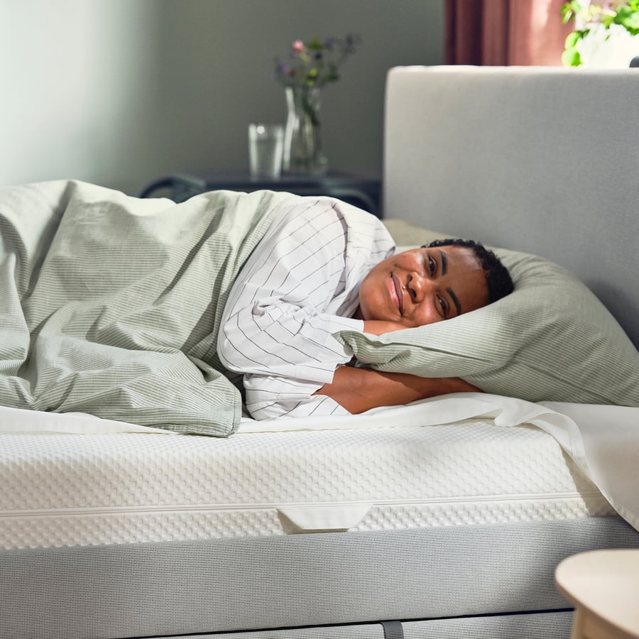 Pessoa a descansar num colchão IKEA ÅBYGDA num quarto
