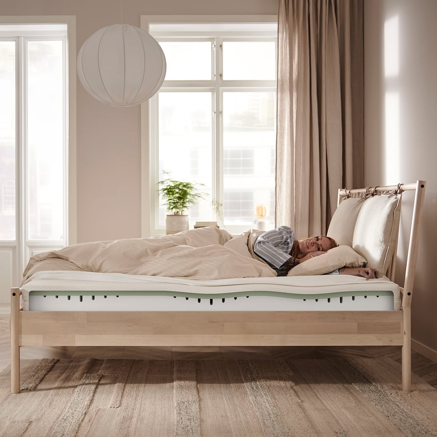 Colchão IKEA ÅBYGDA numa cama de madeira, com as camadas ilustradas