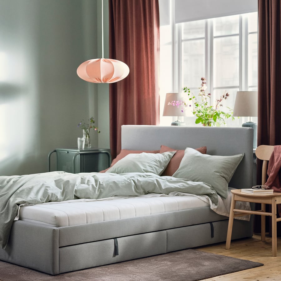 Colchão IKEA ÅFJÄLL numa cama estofada cinzenta num quarto