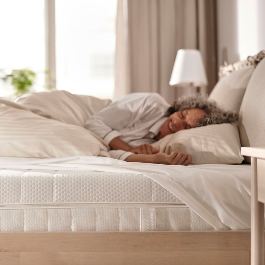 Mulher a dormir de lado num colchão IKEA ÅKREHAMN