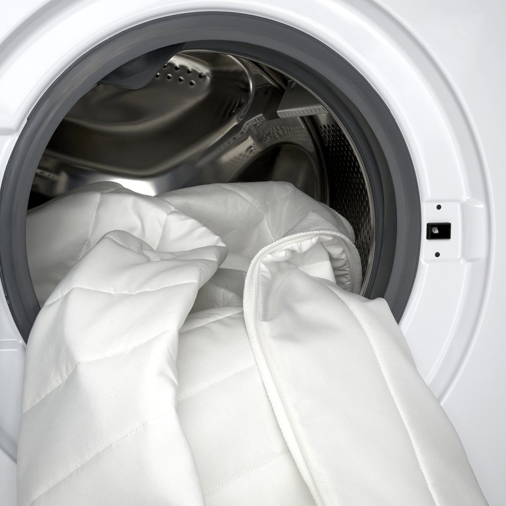 Capa do sobrecolchão IKEA NÄSFJÄLLET a entrar na máquina de lavar roupa