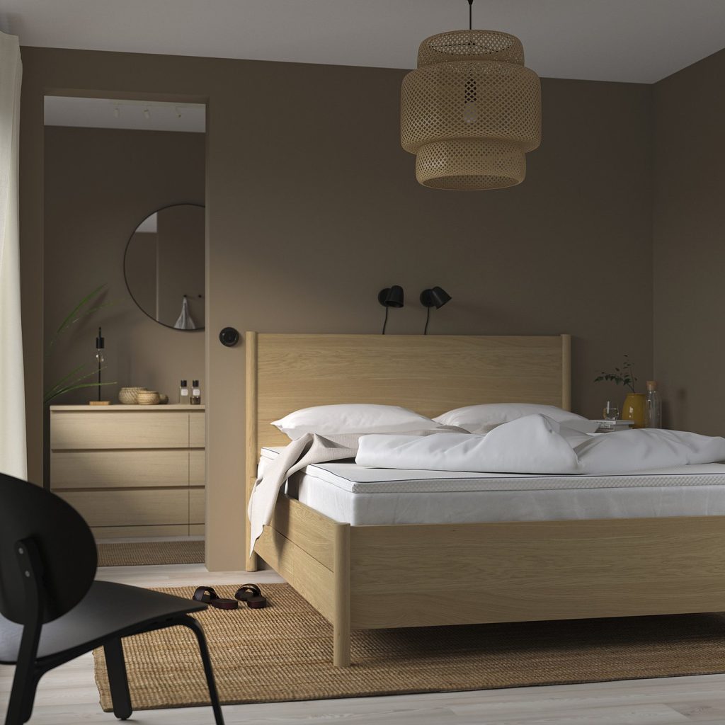 IKEA NÄSTABERG numa cama de madeira clara num quarto de tons quentes