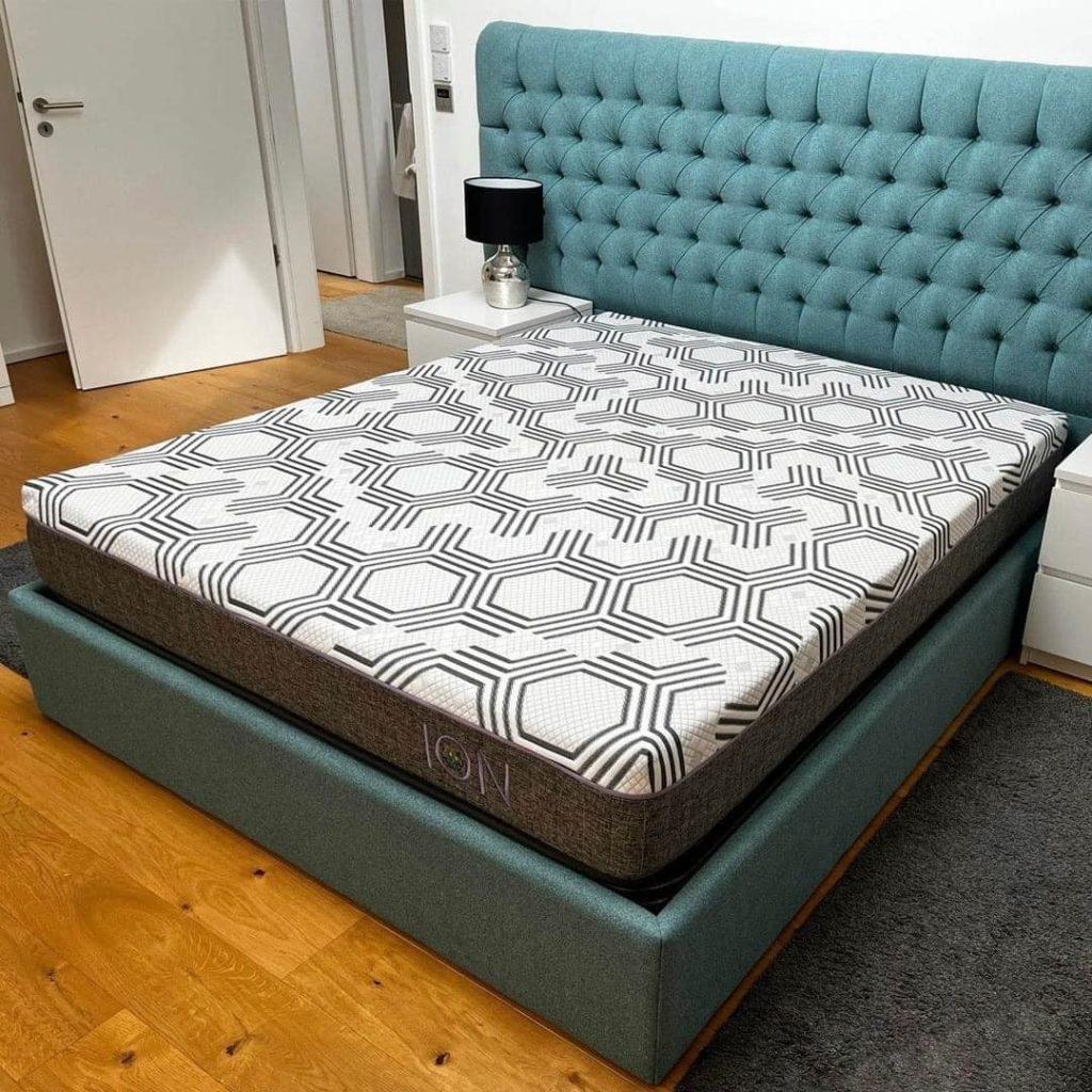 Colchão Mindol ION numa cama estofada azul num quarto com soalho de madeira