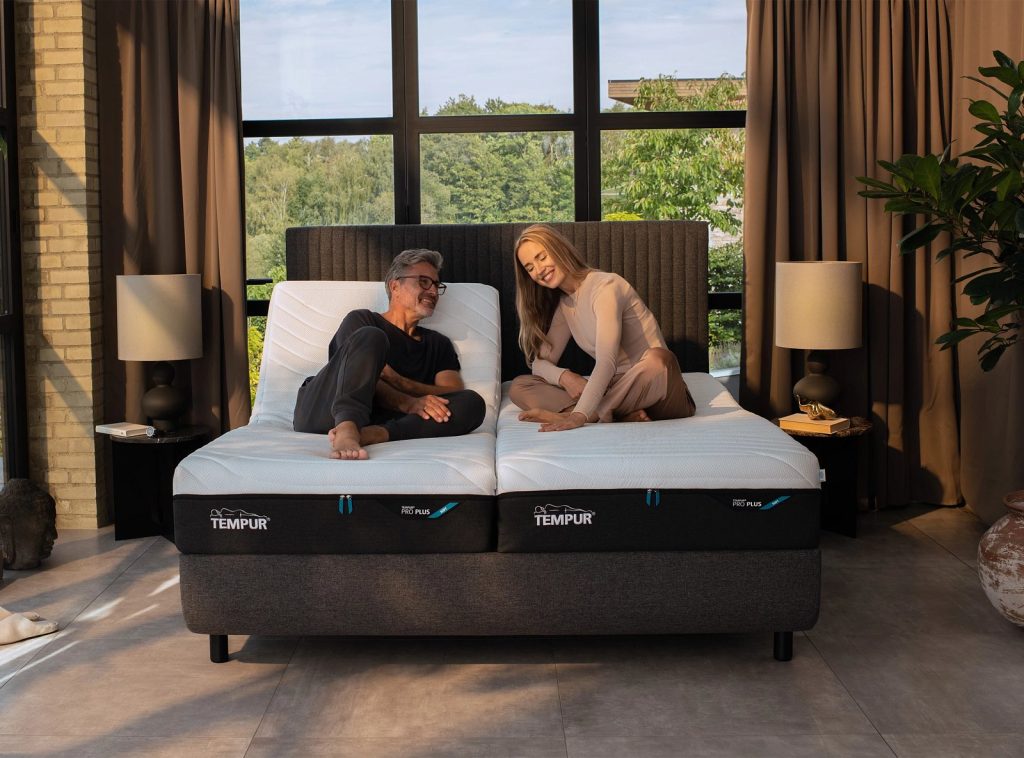 Casal sentado numa cama articulada com colchões Tempur PRO Luxe CoolQuilt
