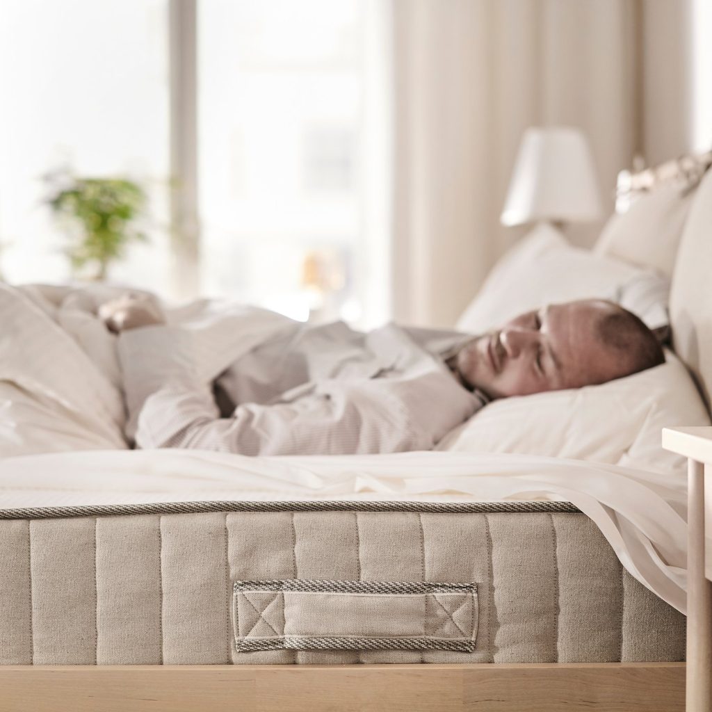 Pessoa a dormir num colchão IKEA VATNESTRÖM num quarto claro