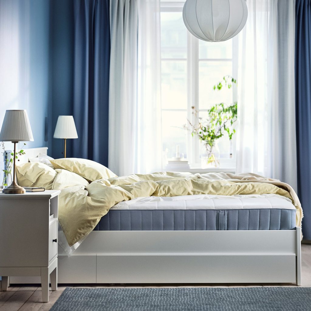 IKEA VESTERÖY numa cama branca num quarto com cortinas azuis