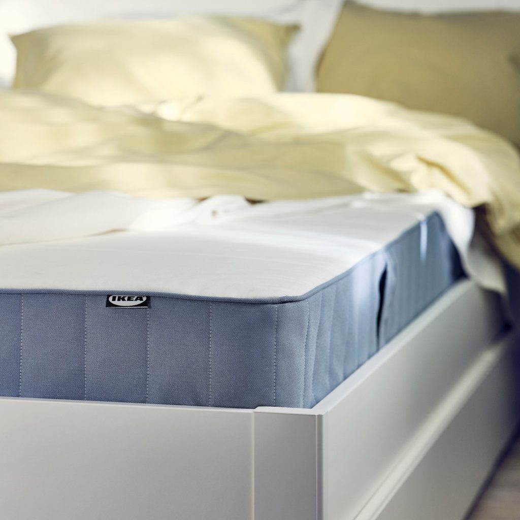 IKEA VESTMARKA, canto do colchão numa cama branca com roupa de cama amarela