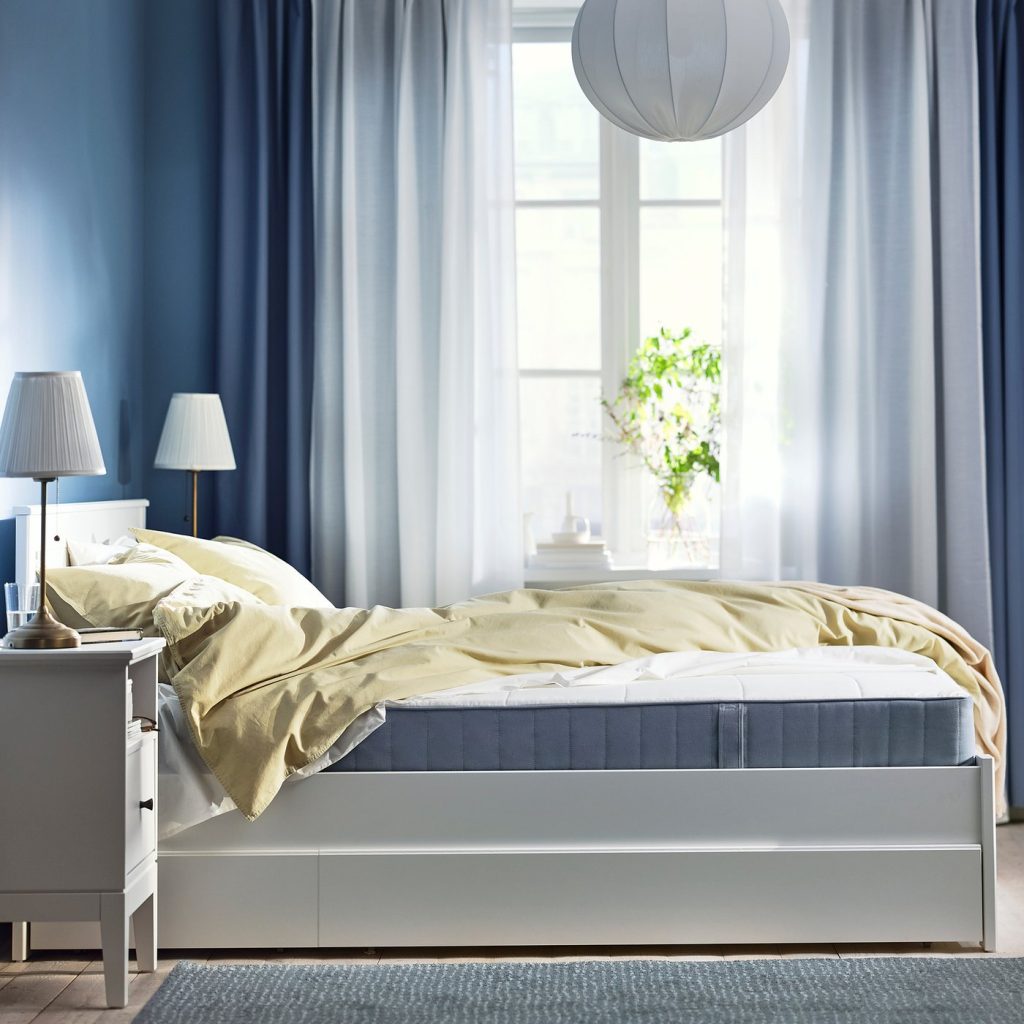 IKEA VESTMARKA numa cama branca num quarto com cortinas azuis